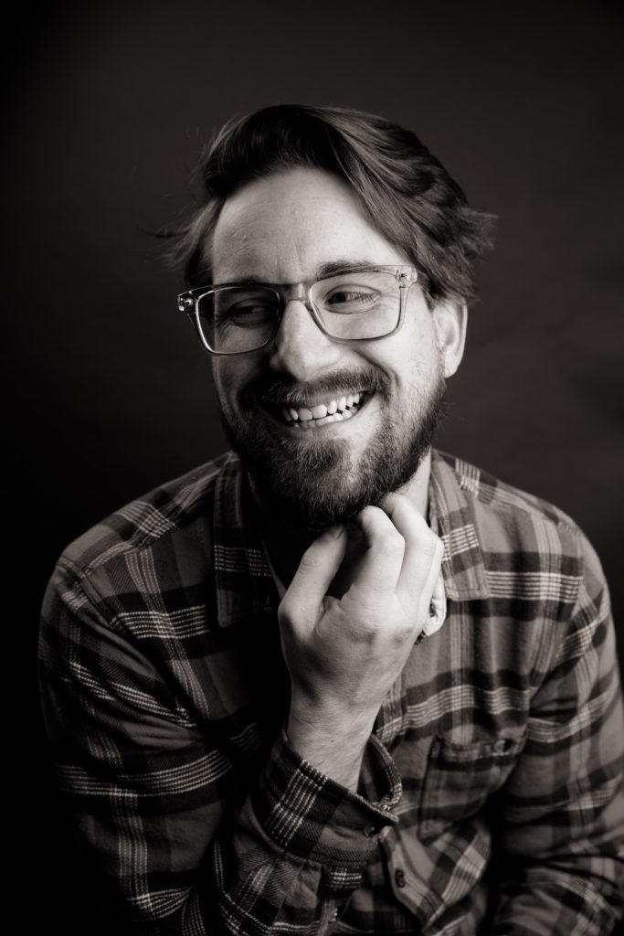 black and white image of man with glasses and beard wearing a flannel shirt