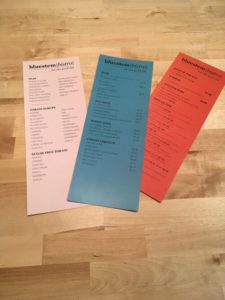 peach, orange, and blue paper menus on a wood table