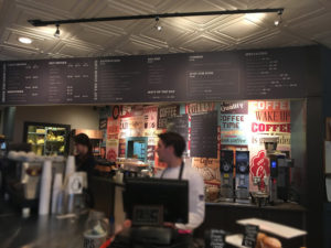 coffee shop register counter with a large menu on the wall