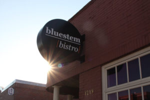 black circular sign with white bluestem bistro logo against a read brick building