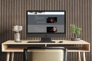 imac sitting between a lamp and plant on a light wood desk